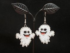 a pair of ghost earrings on a black background