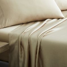 a close up of a bed with sheets and pillowcases on top of it