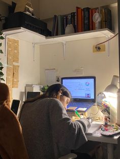 a woman sitting at a desk in front of a laptop computer