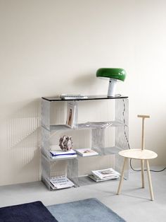 a shelf with books, magazines and a lamp on it next to a chair in a room