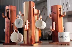 coffee cups and mugs are stacked on wooden stands in the kitchen, with one cup placed between two pieces of wood