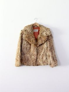 This is an ultra-soft 1970s vintage rabbit fur coat. The brown fur short coat features a large collar, pockets at the waist, and a two hook closure. The interior is lined.  CONDITION In good pre-owned condition with wear consistent with age and use. MARKED SIZE: Small / Medium MEASUREMENTS Bust:             37"  ...     94 cm Length:           24"           ...      61 cm Shoulders:      19"         ...        48.3 cm Sleeves:         17"          ...       43.2 cm Outer Sleeve: 22.5"      ...        57.2 cm For best fit, please compare measurements with a jacket of your own.  HOW WE MEASURE: → Jacket measured lying flat.  → Bust measured armpit to armpit. → Length measured down the center of the back.  → Sleeves measured down the underarm from the armpit to the cuff. → Outer sleeve measur Brown Vintage Fur Coat With Faux Fur Trim, Vintage Fur Coat With Faux Fur Trim, Vintage Faux Fur Mink Coat, Vintage Brown Faux Fur Outerwear, Retro Brown Faux Fur Coat, Vintage Outerwear With Faux Fur Trim, Rabbit Fur Coat, Brown Fur, Vintage Rabbit