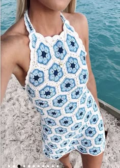 a woman in a blue and white crocheted swimsuit standing on the beach