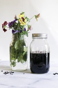 two jars with flowers in them sitting on a table