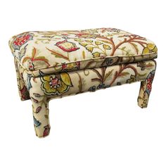 an upholstered foot stool with floral fabric on the top and bottom, sitting in front of a white background