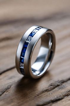 a wedding ring with blue sapphire stones on it sitting on a wooden table in front of the camera