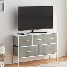 a flat screen tv sitting on top of a white dresser