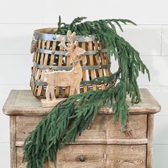 a wooden basket sitting on top of a dresser next to a christmas tree and a deer figurine