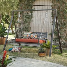 an outdoor swing with cushions and plants in the background