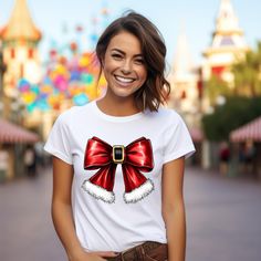 Get ready to spread festive cheer with our Christmas Santa Bow Shirt! This adorable shirt combines the charm of a Christmas coquette style with a delightful retro Christmas tee design, making it the perfect addition to your holiday wardrobe. Featuring a cute pink bow and a cheerful Santa Claus, this Christmas bow shirt is not only stylish but also cozy, resembling a vintage Christmas sweatshirt. Whether you're shopping for yourself or looking for Christmas gifts for loved ones, this girlie Chris Red Christmas Top For Gift, Red Christmas Tops As Gift, Red Christmas Top As Gift, Festive Christmas Top, Red Holiday Shirt For Gift, Holiday Red Shirt As Gift, Red Holiday Shirt Gift, White Festive Christmas Shirt, White Festive Shirt For Christmas