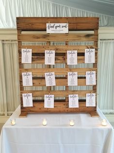 a wooden pallet with seating cards attached to it and candles on the table next to it