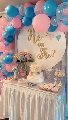 a table topped with a cake and balloons next to a sign that says hey or she?