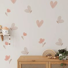 a wall with hearts painted on it next to a wooden cabinet and potted plant