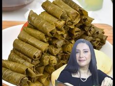 a woman sitting in front of some food on a white plate next to stacks of dumplings