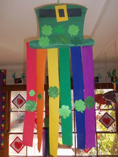 a rainbow colored wind chime hanging in front of a window with shamrocks on it