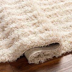 a white rug is laying on the floor with it's edge partially down and its end rolled up