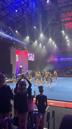 a group of cheerleaders standing on top of a blue court