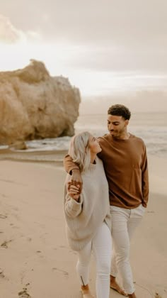 an engaged couple walking on the beach