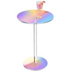 a drink glass sitting on top of a table with a rainbow colored disc around it