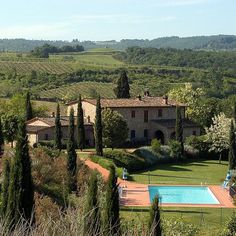 an outdoor swimming pool surrounded by greenery and trees in front of a large house