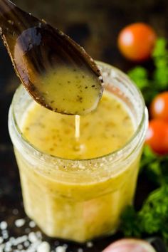 a wooden spoon is sticking into a jar filled with mustard and garlic sauce on a table