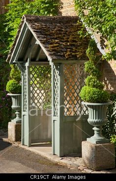 an outdoor gazebo with potted plants on the sides and a fence around it