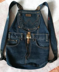 an old jean purse is sitting on the bed with its straps down and it's pocket open