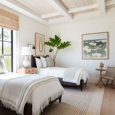 two beds in a bedroom with white linens and pillows on top of each bed