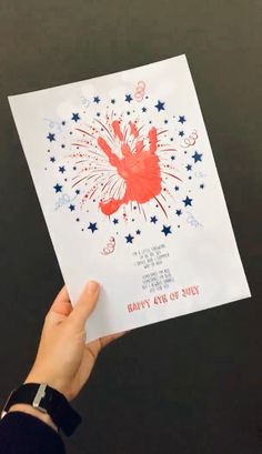 a hand holding up a card with fireworks on it and the words happy new year written in red, white and blue