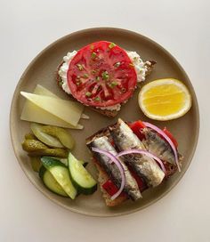 a plate with bread, pickles, tomatoes, cheese and an egg on it