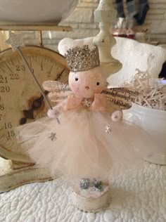 a little angel figurine sitting on top of a table next to a clock