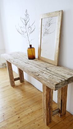 a wooden bench sitting on top of a hard wood floor next to a framed picture