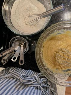 two bowls filled with batter and whisks on top of a counter next to utensils