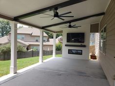 a covered patio with ceiling fans and a flat screen tv mounted to the side of it