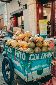 a cart full of coconuts sitting on the side of a road next to a building