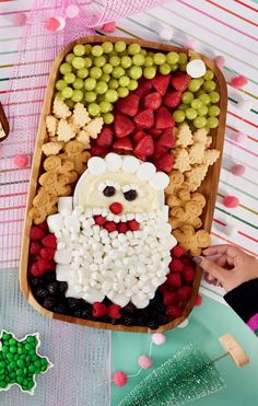 a platter filled with fruit and veggies next to a santa clause cutout