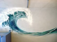 a painting on the wall of a room with a large wave painted on it's side