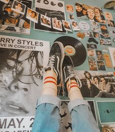 a person with their feet on a skateboard in front of a wall full of posters