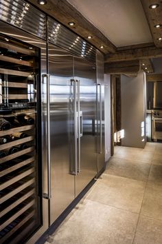 a kitchen with stainless steel refrigerators and wine racks on the wall in front of it