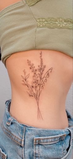 a woman's stomach with a small flower tattoo on her lower back and side