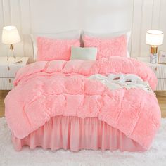 a bed with pink comforter and pillows on top of white fluffy carpeted floor