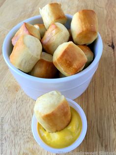 a bowl filled with rolls and mustard on top of a wooden table