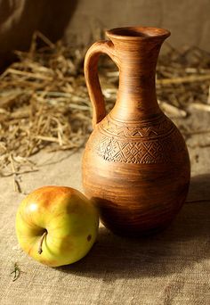 an apple sitting next to a brown vase