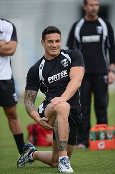 a man sitting on the ground with his foot up in front of him and other men standing behind him