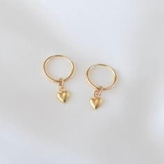 Sweet and cute, these are a pair of small huggie earrings with a dangling gold heart charm. All materials are 14K gold filled and are tarnish-resistant, water-resistant, and hypoallergenic. Hoop measures 12mm in diameter while the heart measures 4 mm in diameter. The heart charm is single sided with a hollow back which makes it very lightweight and comfortable for everyday wear. To put them on, don't pull the hoop apart, instead bend them towards opposite sides like shown in the photo. Happy sho Handmade Gold Huggie Dangle Earrings, Handmade Gold Dangle Huggie Earrings, Handmade Dangle Cartilage Earrings As Gift, Handmade Dangle Cartilage Earrings For Gift, Cute Single Hoop Earring, Gift Dangle Cartilage Earrings, Cute Hypoallergenic Round Hoop Earrings, Handmade Drop Cartilage Earrings As Gift, Cute Small Hoop Earrings For Pierced Ears