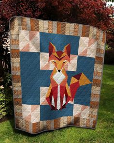 a quilt made to look like a fox sitting on top of a green grass covered field