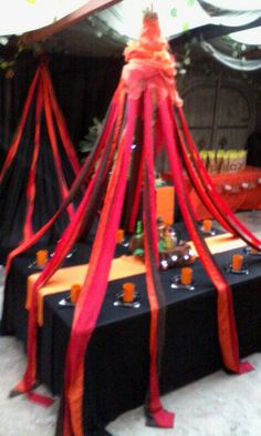 an orange and black table cloth is draped over the top of tables with candles on them