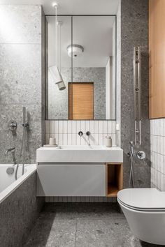 a bathroom with a toilet, sink and bathtub next to a mirror on the wall