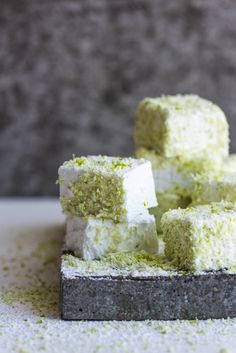 several pieces of green cake sitting on top of a white table cloth covered in powdered sugar