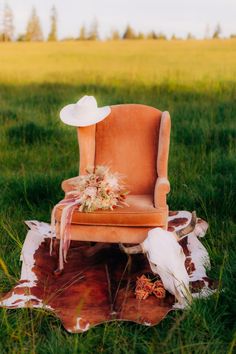 an old chair sitting on top of a cow skin rug in the middle of a field